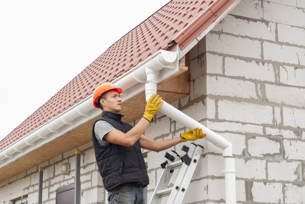 Worker installing a roof gutter