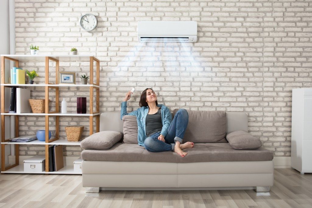woman sitting in a sofa, enjoying the cool temperature from aircon
