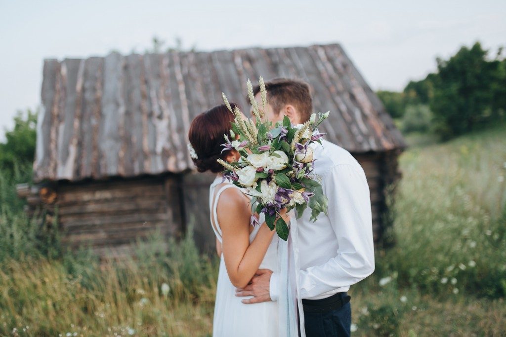 Couple kissing after wedding with wooden house in the background