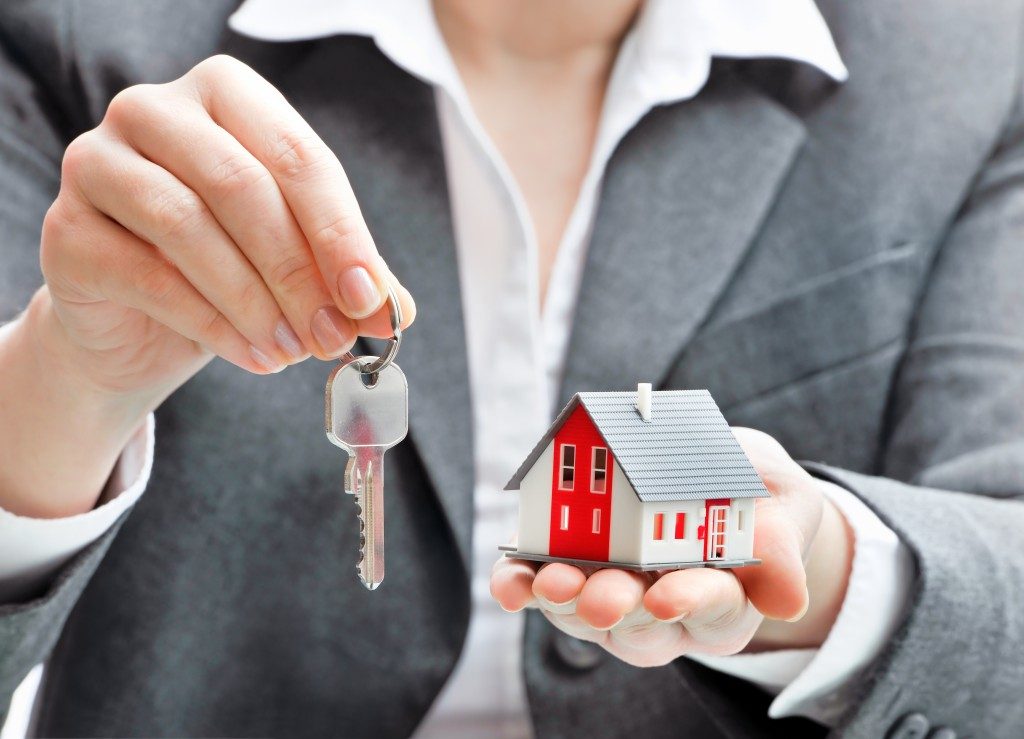 woman holding a house model and keys