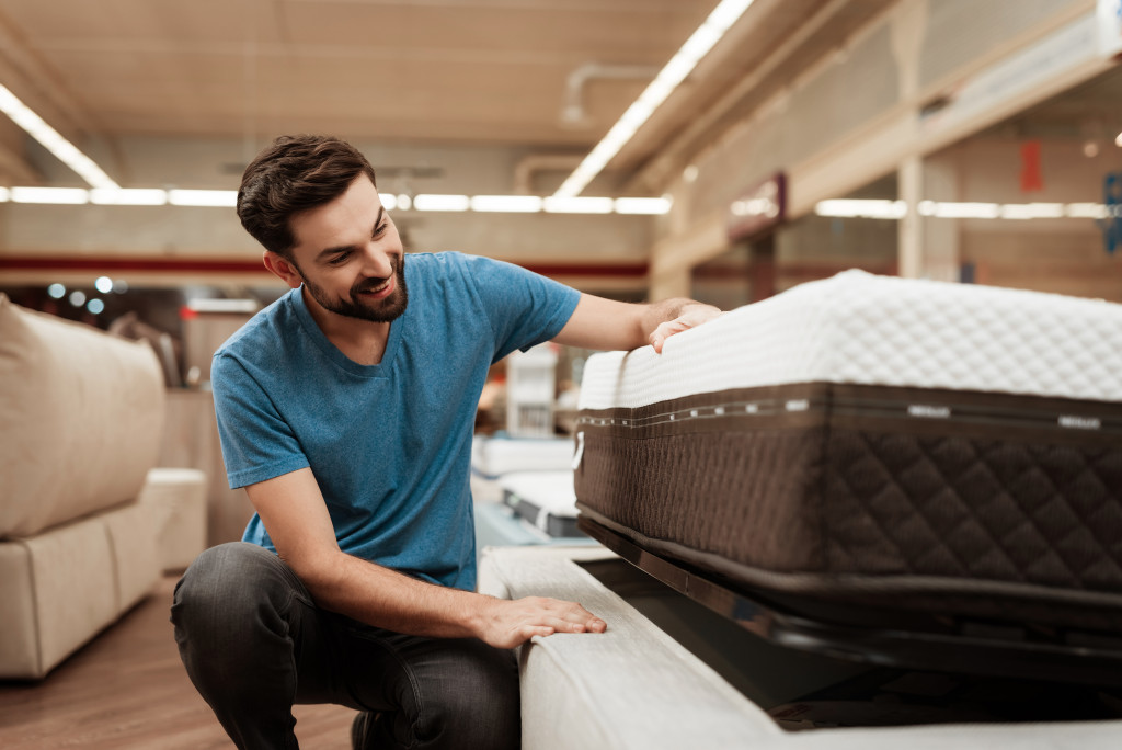 A man looking the bottom of his bed