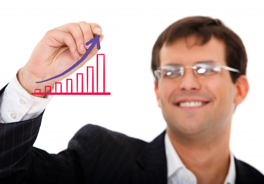 Smiling businessman drawing a grow graph on a transparent board.