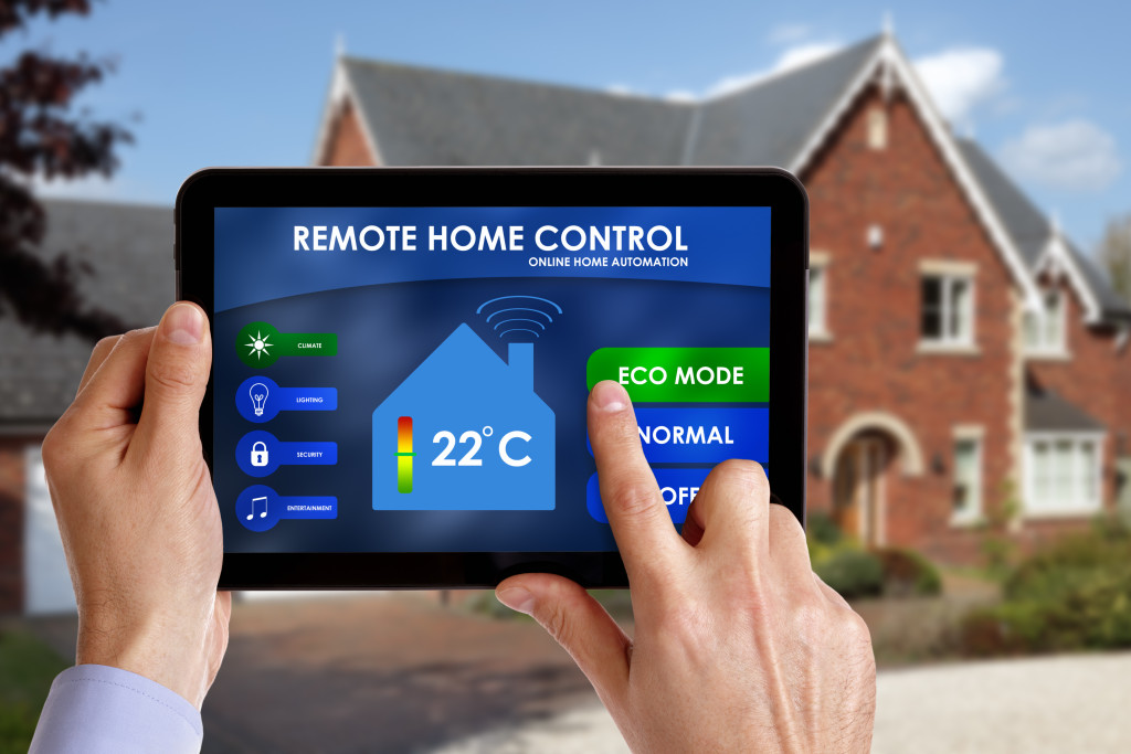 a man holding a tablet and using it as a remote control for monitoring his home