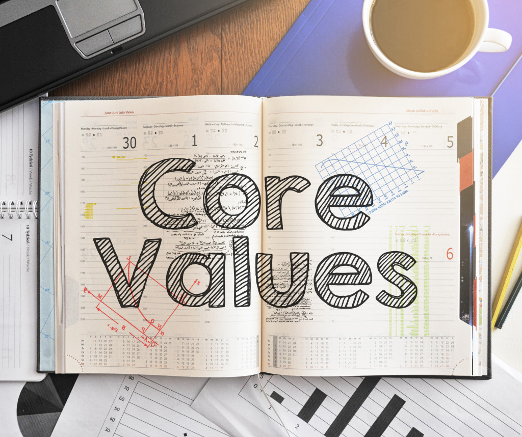 Words core values projected on a notebook with a cup of coffee, paper, and laptop beside it. 