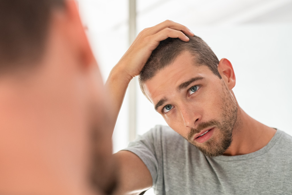 guy looking at his face in mirror,