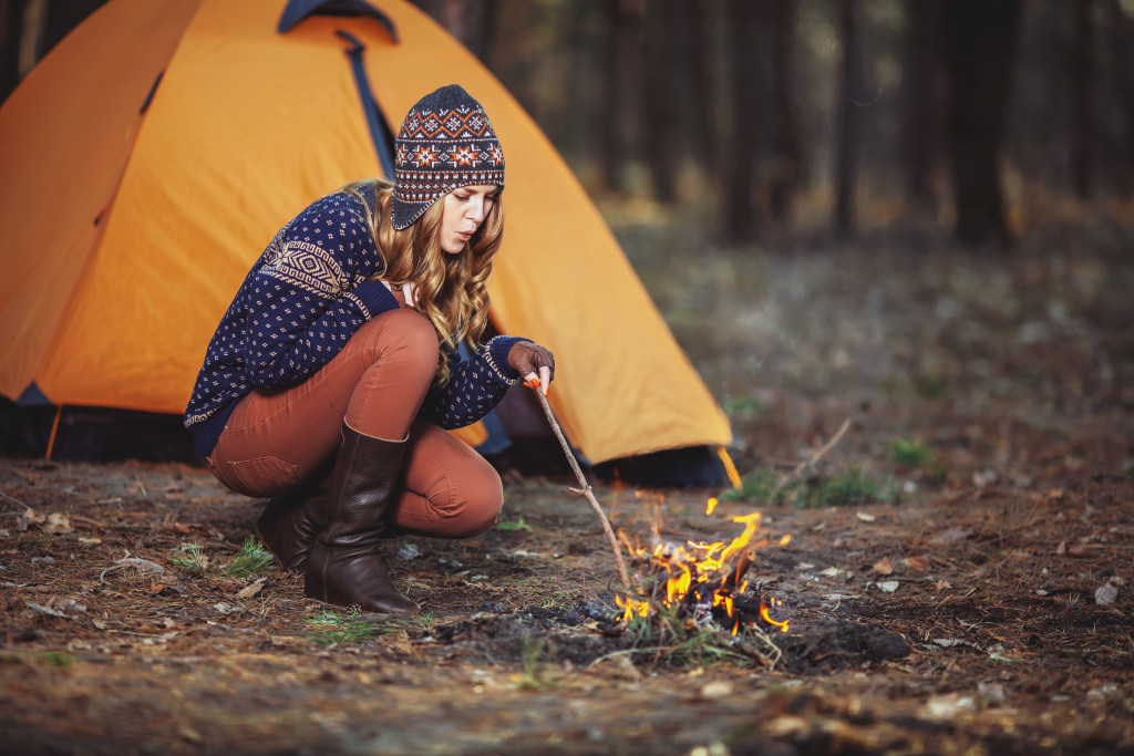 Woman starting a fire in the woods